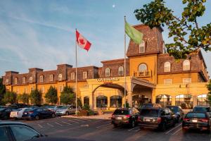 un edificio con dos banderas canadienses y coches estacionados en un estacionamiento en Courtyard by Marriott Waterloo St. Jacobs, en Waterloo