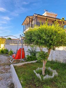 uma pequena árvore num quintal ao lado de um edifício em Troi beach house em Vlorë