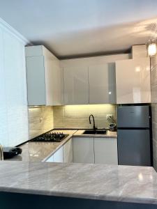 uma cozinha com armários brancos e um frigorífico preto em Piligrim Kazbegi em Stepantsminda