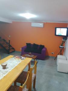 sala de estar con sofá púrpura y TV en Mí cielo en Huerta Grande