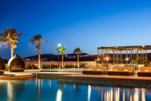 una piscina con tumbonas y palmeras por la noche en Sheraton Chihuahua Soberano, en Chihuahua