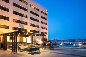 un patio del hotel con mesas y sillas frente a un edificio en Sheraton Chihuahua Soberano en Chihuahua