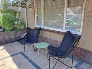 two chairs and a table in front of a building at Appartement aan Zee in Noordwijk