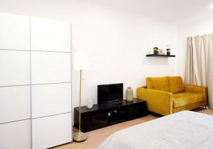 een slaapkamer met een gele stoel en een televisie bij Apartment Ajuda Tagus (ground floor) in Lissabon