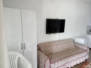 sala de estar con sofá y TV en la pared en Ayşen Ablanın Yeri, en Muğla