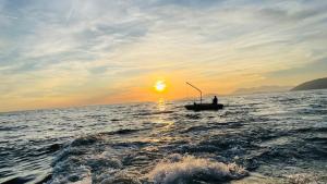 um homem num barco no oceano ao pôr-do-sol em Rambuje Resort em Lezhë