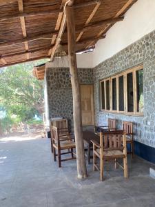 eine Terrasse mit Stühlen, einem Tisch und einem Baum in der Unterkunft Soul Rebel Lodge & Backpackers in Nkhata Bay
