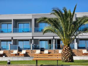 a palm tree in front of a building with a bench at Sea Coast Resort Halkidiki in Yerakiní