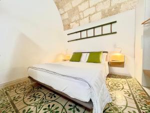 een slaapkamer met een bed met witte lakens en groene kussens bij B&B Suite Amare Polignano in Polignano a Mare