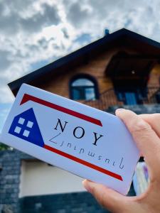 a person holding a now sign in front of a house at NOY Guest House B&B in Vanadzor