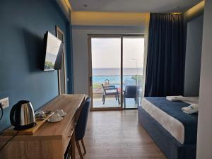 a hotel room with a bed and a desk with a view of the ocean at Sea Coast Resort Halkidiki in Yerakiní