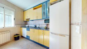 une cuisine avec des armoires jaunes et bleues et un réfrigérateur dans l'établissement CazorSierra, bonita vivienda en Cazorla, à Cazorla