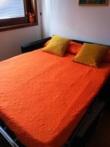 1 cama con edredón de naranja y 2 almohadas en Mi casa es tu casa, en Pordenone