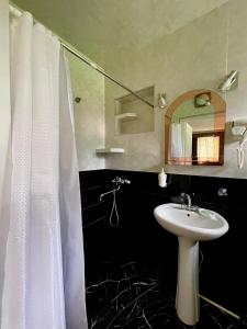 uma casa de banho com uma cortina de chuveiro branca e um lavatório. em Piligrim Kazbegi em Stepantsminda