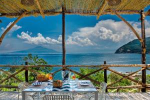 a table with chairs and a view of the ocean at Villa Degli Dei Maestrale in Vico Equense