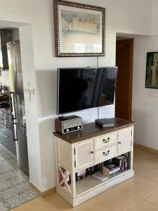 a flat screen tv sitting on top of a wooden entertainment center at Casa la Vida - Golf villa with private pool in Alhama de Murcia