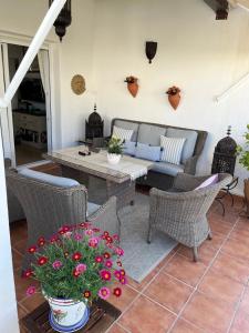a patio with a table and chairs and flowers at Casa la Vida - Golf villa with private pool in Alhama de Murcia