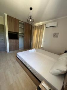 una camera da letto con un grande letto bianco e una televisione di Tasos Cozy House 1 a Città di Lefkada
