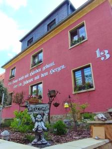 um edifício cor-de-rosa com uma placa à frente. em Ferienwohnung "Spatzennest" em Pirna