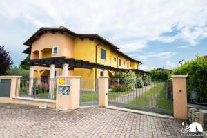 ein gelbes Haus hinter einem Zaun mit einem Tor in der Unterkunft Casa della Rocca in Manerba del Garda