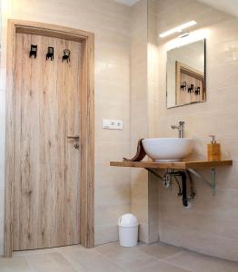 uma casa de banho com um lavatório e uma porta de madeira em Lux Apartman Bük em Bük