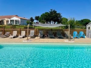 a swimming pool with blue chairs and a fence at Les Gites de la Richardiere in Saint-Révérend