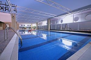 a large swimming pool with blue water in a building at Park Regis Lotus Hotel in Manama