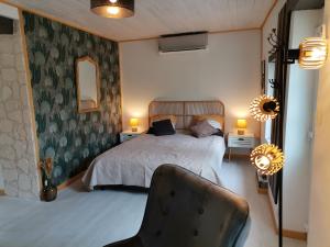 a bedroom with a bed and a chair in it at Love Room avec spa in Nérac