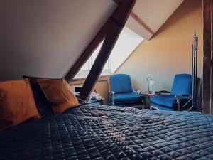 a bedroom with a bed and two blue chairs at Boutique Hotel Bajoene in Middelburg