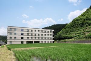 ein weißes Gebäude mit einem Grasfeld davor in der Unterkunft Fairfield by Marriott Gifu Takayama Shirakawa Go in Takayama