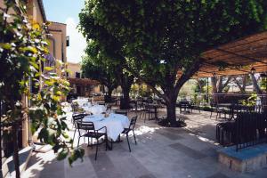 un patio con mesas, sillas y árboles en Auberge du Redier en Colomars