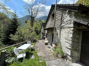 a stone house with a table and chairs on a porch at Rustico al fiume Verzasca 