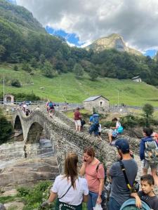 a group of people walking over a stone bridge at Rustico al fiume Verzasca 