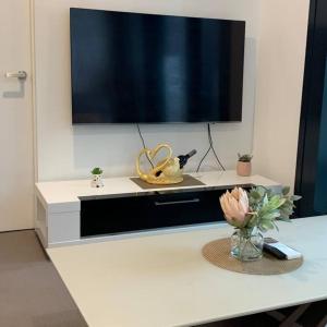 a tv on top of a white table with a vase of flowers at CBD Spacious Two Bedrooms Apartment in Melbourne