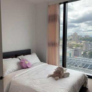 a teddy bear sitting on a bed with a window at CBD Spacious Two Bedrooms Apartment in Melbourne