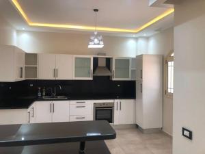 a kitchen with white cabinets and a black counter top at Moubark 6 Villa 1 in Hurghada