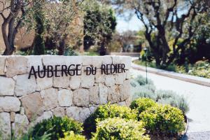 un cartel en una pared de piedra con arbustos en Auberge du Redier en Colomars