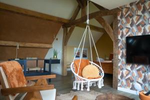 een kamer met een hangstoel en een tv bij TweeZeven in Guelle