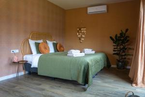 een slaapkamer met een bed met een groene deken bij TweeZeven in Guelle