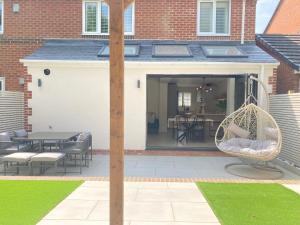 a patio with a swinging chair and a table at Greensfield Close 