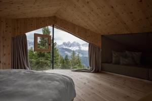 um quarto com uma cama e uma grande janela em Odles Lodge em Bressanone