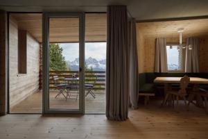 uma sala de estar com uma mesa e uma varanda em Odles Lodge em Bressanone