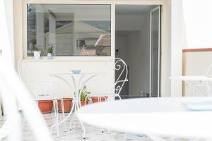 a white table and chairs in front of a window at Un Posto al Mare in Santa Maria di Castellabate