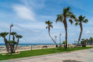 una fila de palmeras en una acera cerca de la playa en Un Posto al Mare, en Santa Maria di Castellabate