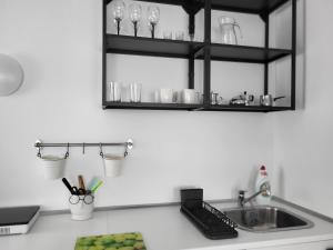 a kitchen counter with a sink and black shelves at JOREDA apartamentai in Biržai +2 photos