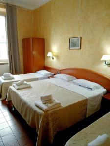 ローマにあるホテル フェラーリのホテルルーム内のベッド2台(タオル付)