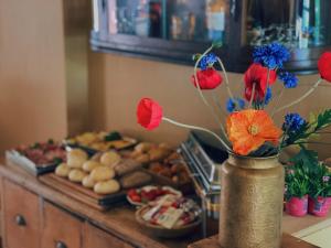 Boutique Hotel Bajoene في ميدلبورغ: مزهرية مليئة بالورود على طاولة مع الطعام