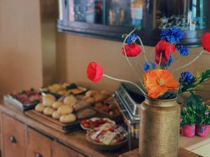 un vaso pieno di fiori su un tavolo con cibo di Boutique Hotel Bajoene a Middelburg