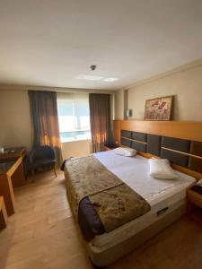 a bedroom with a large bed and a desk at Pınar Elite Hotel in Adana