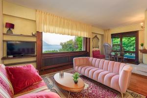 a living room with a pink couch and a large window at Villa Rivabella - By Impero House in Ghiffa